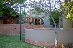 a house with a brick wall and a tree at Bel Tramonto in Bloemfontein