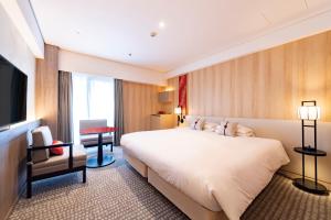 a hotel room with a large bed and a chair at Kyoto Tokyu Hotel in Kyoto