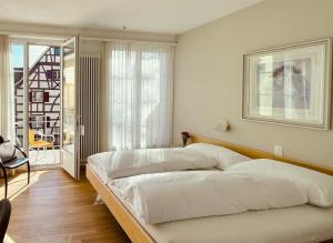 a bedroom with a large white bed and a balcony at Hotel Rössli in Basel