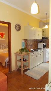 a kitchen with white cabinets and a table and a bed at center apartments in Lefkada Town