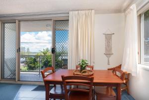 a dining room with a table and chairs and a balcony at Yamba Towers 2 - LJHooker Yamba in Yamba
