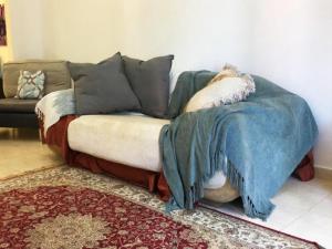 un sofá con una manta en la sala de estar en Octavius Holiday Home, Large 2 Bedroom Apartment near Global Village & Outlet Mall en Dubái