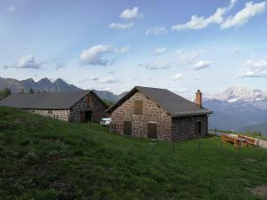 dois edifícios numa colina com montanhas ao fundo em Baita Casera Caviazza em Falcade