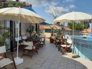 a patio with tables and umbrellas next to a pool at Hotel Flesvos in Pefkochori