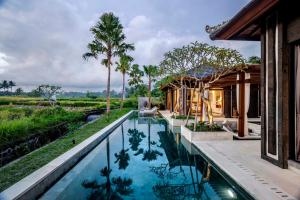 a pool in the backyard of a house with palm trees at Villa Mimpi by BaliSuperHost in Ubud