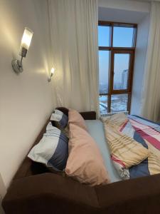 a unmade bed in a room with a window at Mini cozy corner #1 in Almaty