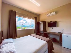 a bedroom with a bed and a desk and a window at Pousada Buena Vista in Capitólio