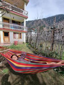 a child laying in a hammock in a house at Uncle Nomad in Manāli