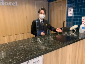 a man in a mask standing at a counter at Smile Hotel Sendai-Kokubuncho in Sendai