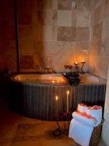 La salle de bains est pourvue d'une baignoire avec des bougies et des serviettes. dans l'établissement Alice in Cappadocia, à Uçhisar