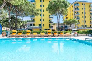 a swimming pool with chairs and a building in the background at Costa Del Sol in Lido di Jesolo