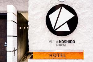 ein Schild für ein Hotel an der Seite eines Gebäudes in der Unterkunft VILLA KOSHIDO kotoni in Sapporo
