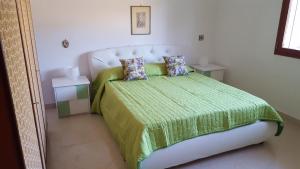a bedroom with a bed with a green blanket and pillows at Villa Sogno sulla Spiaggia in Fontane Bianche