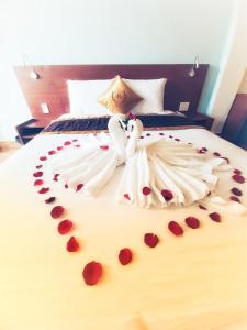 dos mujeres vestidas de novia acostadas en una cama con rosas en Rinny Hotel en Da Lat