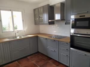 a kitchen with gray cabinets and a sink and a window at Villa Betonia in Punta Prima