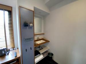 a bathroom with a sink and a mirror at UMEDAHOLIC HOTEL in Osaka
