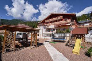 einen Spielplatz vor einem Haus mit einem Gebäude in der Unterkunft Family Hotel Andes - Only for Family in Vigo di Fassa