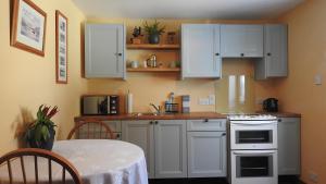 a kitchen with white cabinets and a table with a tablecloth at Invercassley Cottage B & B Suite in Lairg