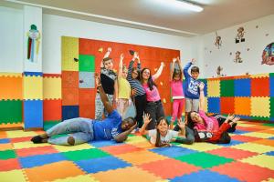 un gruppo di bambini stesi sul pavimento con le mani in alto di Family Hotel Andes - Only for Family a Vigo di Fassa