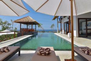 a pool at a resort with chairs and umbrellas at Villa Lakshmi in Temukus