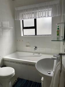 y baño con bañera, aseo y lavamanos. en Herolds Bay Accommodation - Smalstaan Upstairs, en Herolds Bay