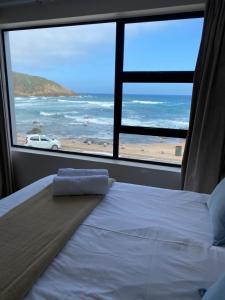 1 dormitorio con cama y vistas a la playa en Herolds Bay Accommodation - Smalstaan Upstairs, en Herolds Bay