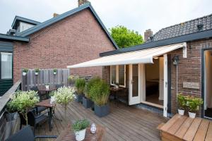 a patio with tables and chairs and a white awning at Bed & Breakfast De Vier Seizoenen in Lisse