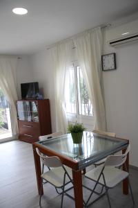 une salle à manger avec une table en verre et deux chaises dans l'établissement Magnífica casa con jardín y barbacoa en Roses, à Roses