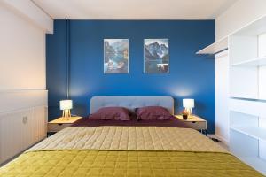 een slaapkamer met blauwe muren en een bed met 2 lampen bij Le petit Manhattan - Appartement privé de 45 m2 - 2 à 4 personnes - Parking privé in Metz