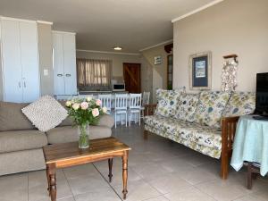 a living room with a couch and a table with a vase of flowers at Herolds Bay Accommodation - Smalstaan Downstairs in Herolds Bay
