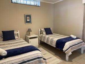 a bedroom with two beds and a table with a lamp at Herolds Bay Accommodation - Smalstaan Downstairs in Herolds Bay