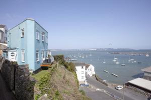 a blue house on a cliff with boats in the water at Cliff Cottage, Brixham in Brixham