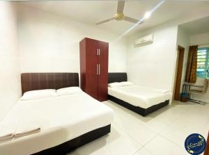 a bedroom with two beds and a cabinet in it at Motel Fasa2B in Seri Manjung