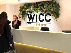 eine Frau, die auf einem Handy an der Visa-Rezeption spricht in der Unterkunft Hotel WICC in Wageningen