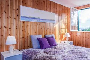 a bedroom with wooden walls and a bed with purple pillows at Vivenda Gomes AL in Porto Martins