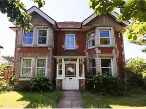 Casa de ladrillo rojo con puerta blanca y ventanas en Arbour House B&B en Swanage