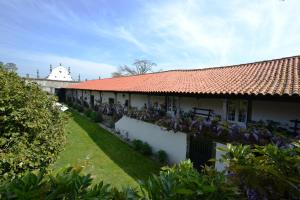 a white building with a red roof with purple flowers at Quinta de Santa Baia in Gaifar