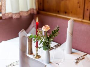 a table with two candles and a vase with a flower at Hotel Gasthof Blaue Quelle in Erl