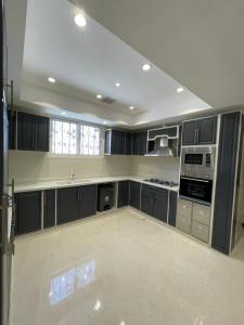 a large kitchen with black cabinets and white appliances at Royal AlUla Villa in AlUla