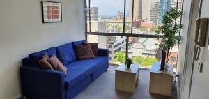 a blue couch in a room with a large window at 2 bedrooms CBD FREE Tram apartment (Melb Central, China Town, Queen Victoria Market, Melbourne University, RMIT, etc) in Melbourne