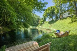 a bench sitting next to a river next to a river at Hotel Gasthof Blaue Quelle in Erl