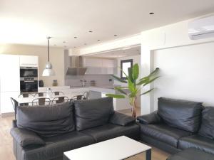 Una sala de estar con un sofá negro y una cocina. en Aiguaneu Luxury Nàutic, en Blanes