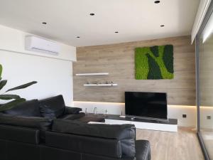 Una sala de estar con un sofá negro y un televisor de pantalla plana. en Aiguaneu Luxury Nàutic, en Blanes