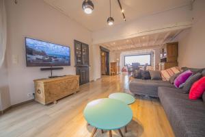 a living room with a couch and a table and a tv at La villa Émilie in Durbuy