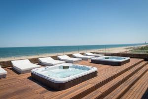 a hot tub sitting on top of a deck next to the beach at Hotel Commodore in Cervia