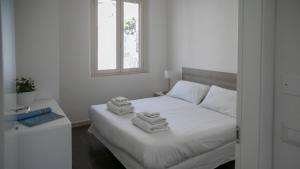 ein Schlafzimmer mit einem weißen Bett mit Handtüchern darauf in der Unterkunft Luminosa - Cala Gonone in Cala Gonone