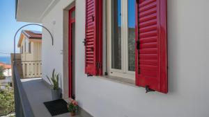 zwei rote Fensterläden auf einem weißen Gebäude in der Unterkunft Luminosa - Cala Gonone in Cala Gonone