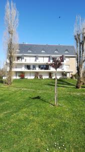 a large white building with a tree in a field at Près de la mer in Le Pouliguen