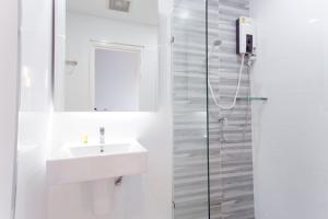 a white bathroom with a sink and a shower at ABIZZ Hotel KwanPhayao in Phayao