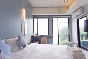 ABIZZ Hotel KwanPhayao في فاياو: سرير أبيض كبير في غرفة بها نوافذ